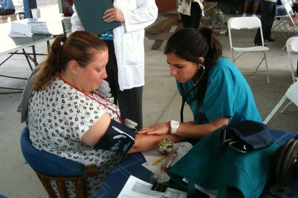 nurse checking blood pressure on a patient under a tent