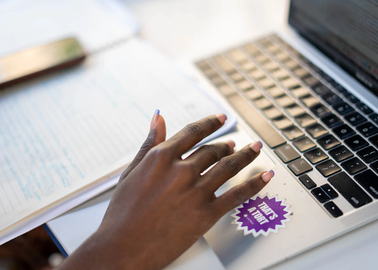 A closeup of a hand scrolling a mousepad. A sticker on the laptop reads, "That's a Tort"