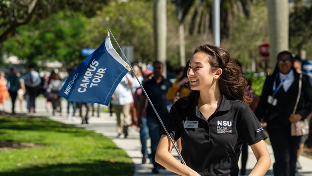 Staff walking on outdoors with group giving campus tour