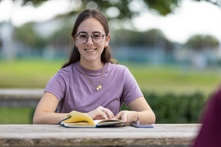 Student reading book on campus outdoors
