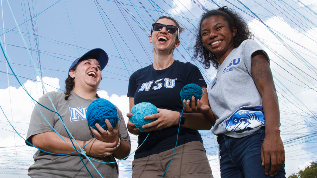 Group of NSU students laughing together while doing a club activity outdoors