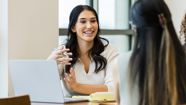 Woman with a laptop smiles and talks to a student