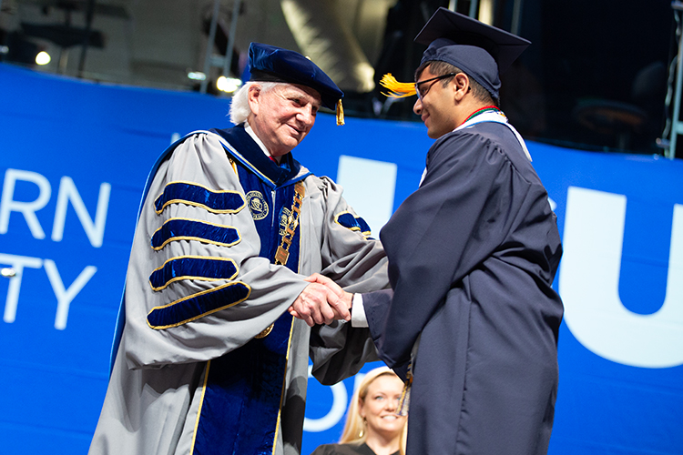 NSU president Hanbury shakes the hand of a graduating student.