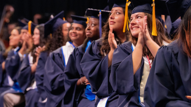 Graduates in caps and gowns applauding