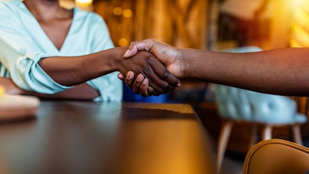 Two people handshake recruitment on table.