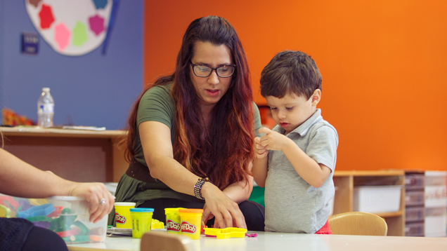 Early education teacher and child using play-doh