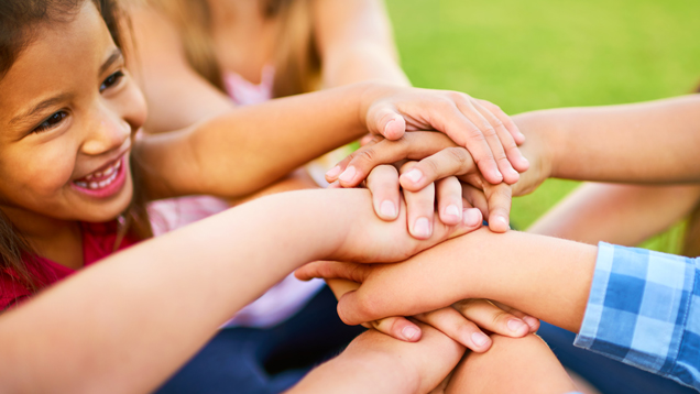 Group of kids stacking their hands creating positive connections