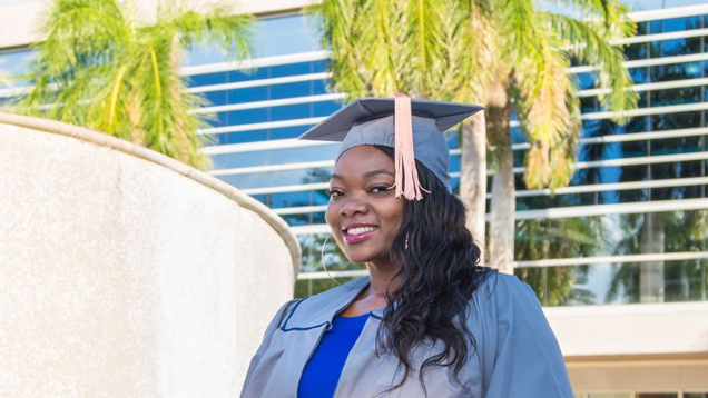 NSU edge graduate student in campus outdoors with cap and gown