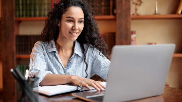 Woman sitting at table using computer and typing