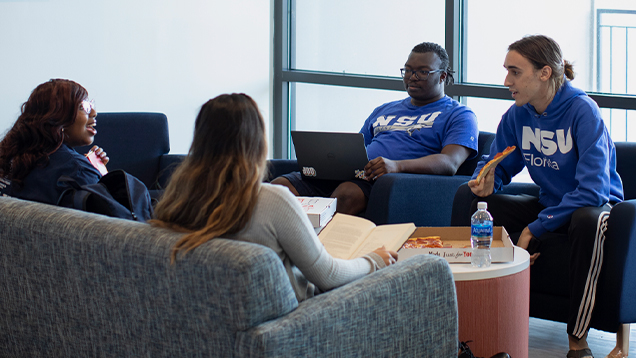 Group of NSU students talking and eating pizza