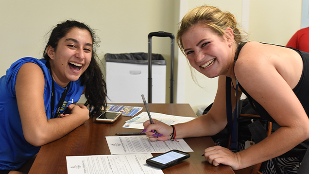 NSU students smiling and signing a document