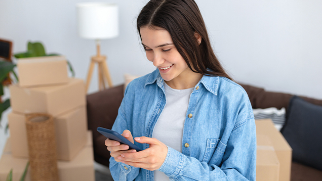 Student using her phone next to boxes