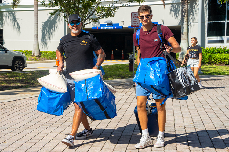 Two men with luggage moving out of campus