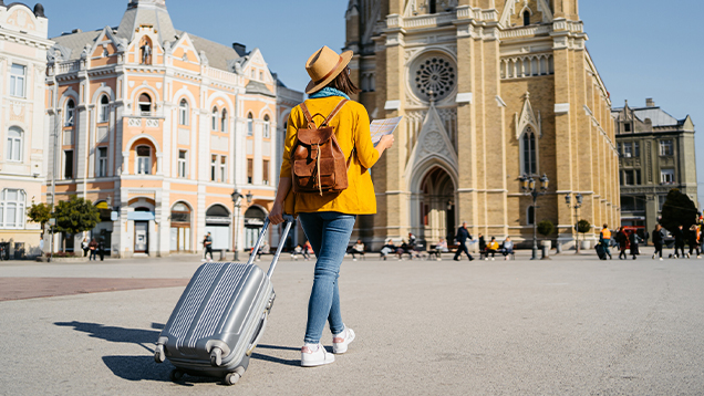 Woman with luggage using a map outdoors