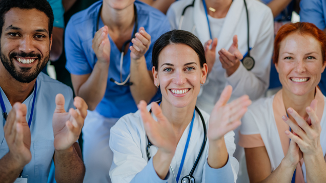 Group of medical professionals looking at camera clapping.