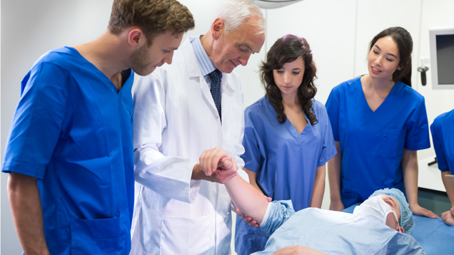 Medical students examining patient arm with professor assistance