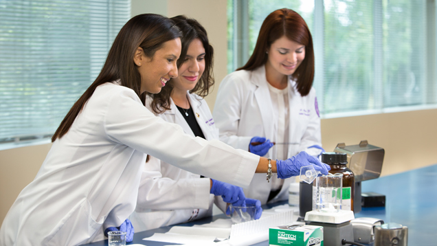 Three female students training and collaborating in lab