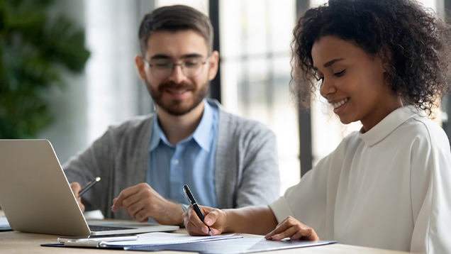 Woman signing a document next to a man