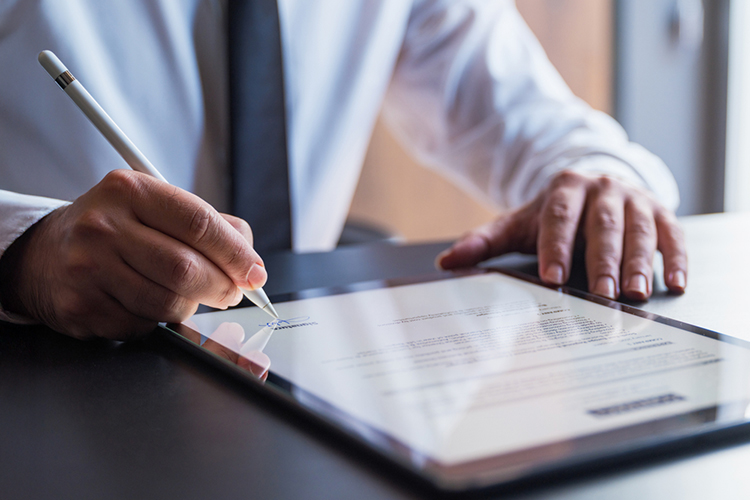 Man signing a document on a digital tablet close up
