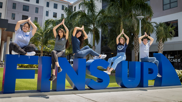 Fins up students in top of sign