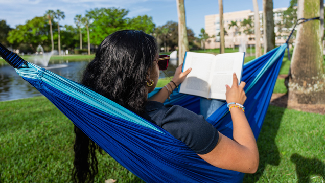 NSU student reading book on campus hammock