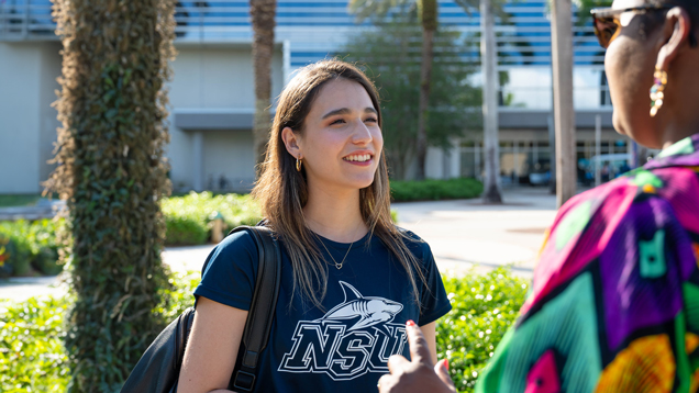 Student speaking with school faculty staff on campus outdoors