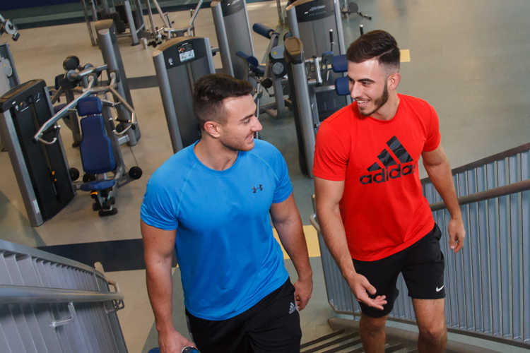 Two NSU sharks at the gym going up the stairs