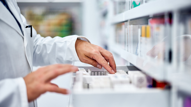 Male pharmacist choosing medicine from drawer