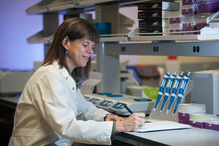 Scientist writing in her notebook in a lab