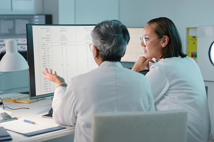 Two scientists looking at a computer monitor and discussing results