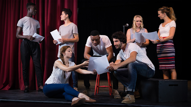 Actors reading their scripts on stage in theatre