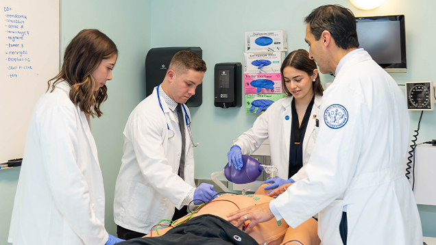 Doctor and students using medical equipment on a manikin