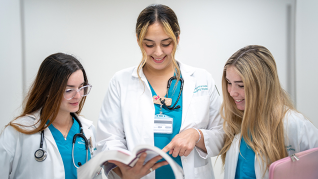 Group of NSU nurses looking at a book