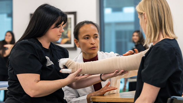 Physical therapist and professor examining the arm of a woman