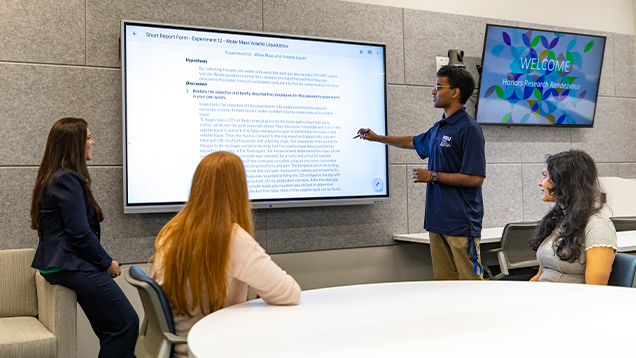 Professor and students view a presentation on a screen