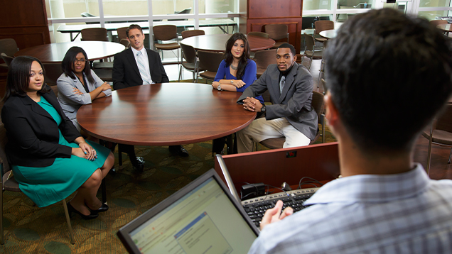 Student speaking to a group of people sitting at a table