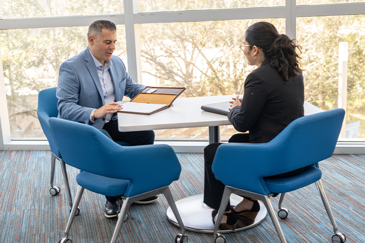 Professor and student talking while sitting at a table